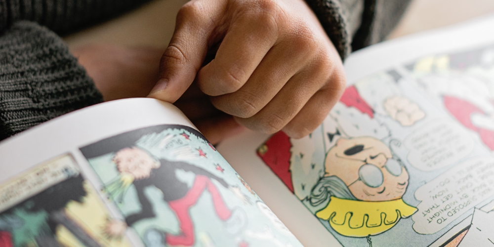 a hand resting on an open graphic novel