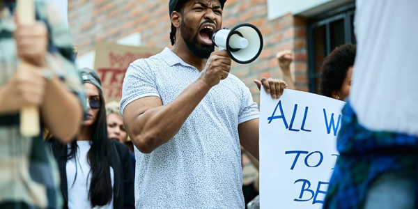 adult speaking in megaphone walking in a crowd of people holding signs