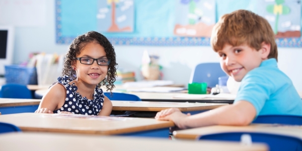 two middle school-age children sitting at desks in a classroom