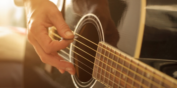 hand holding a pick and playing a guitar