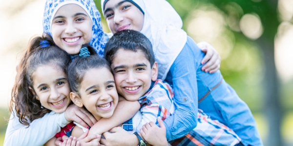 two smiling adults and three children