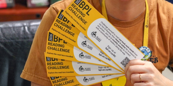 adult holding a fan of Reading Challenge bookmarks