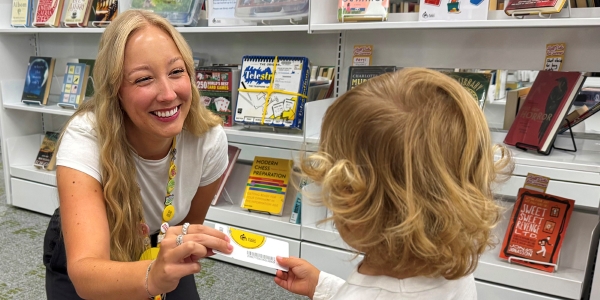 smiling staff member handing a BPL card to a young child