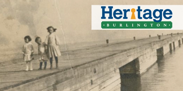 Early 1900s photo of three children walking on a Burlington Beach pier with Heritage Burlington logo