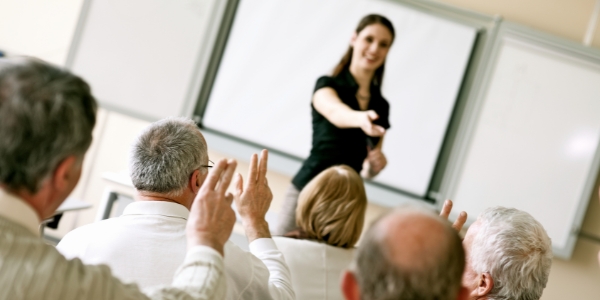 group of older adults seated in a class setting with an instructor standing in front. 