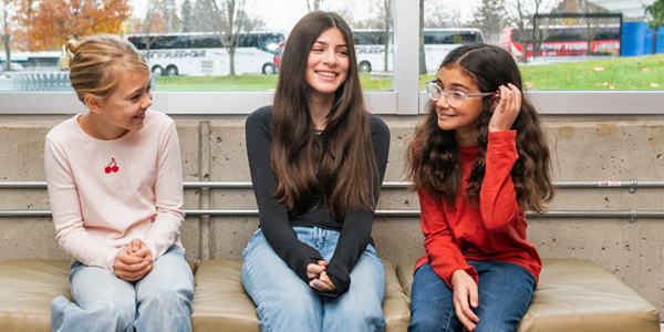 three teens sitting on a bench