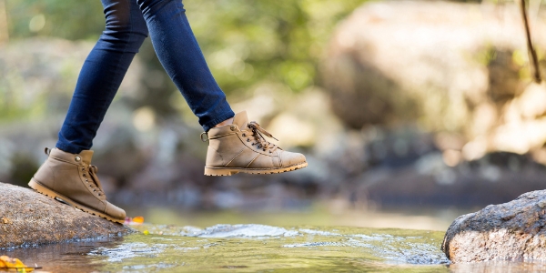 person stepping on rocks to cross a creek