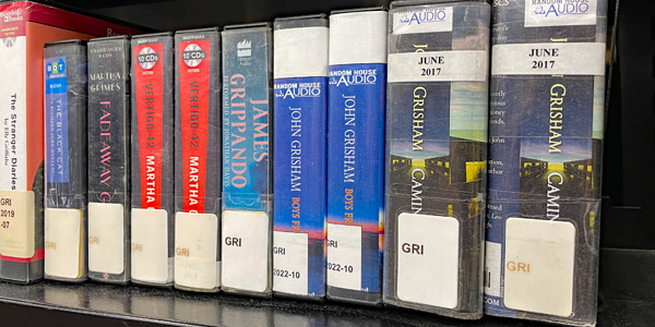row of ten audiobooks-on-cd on a libary bookshelf