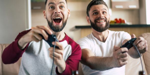 two smiling adults using gaming controls seated together.