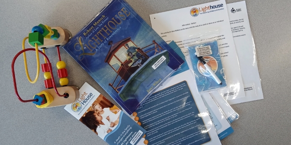 picture book with various laminated activity cards and a pamphlet from Lighthouse for Grieving Children