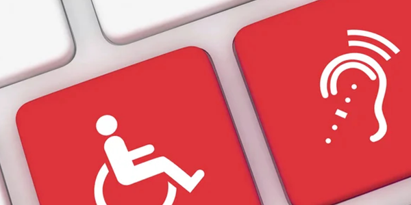 close-up of a white computer keyboard with two red keys depicting icons for wheelschair and hearing