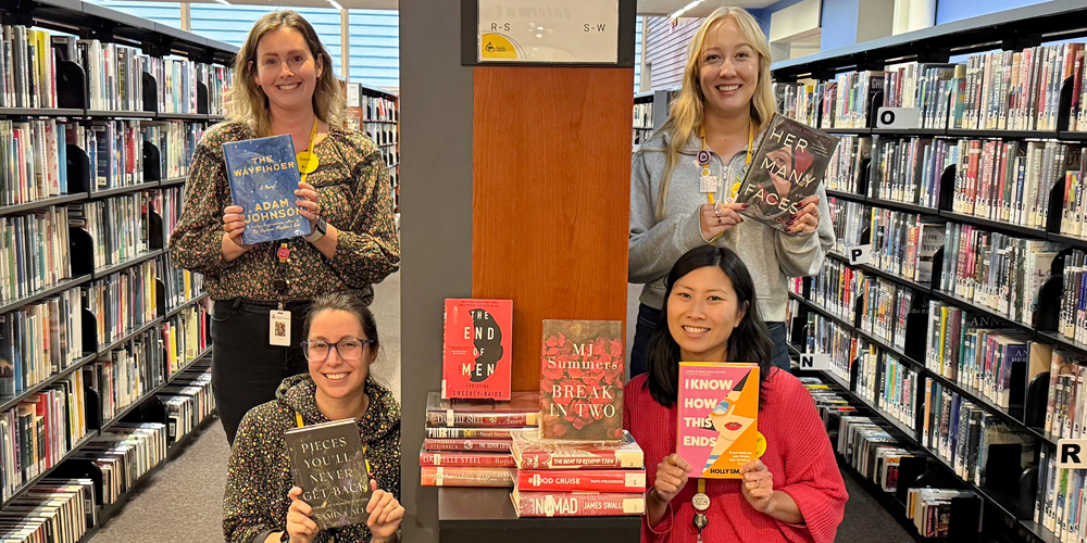 four staff members each holding up a book