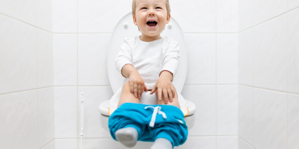 laughing toddler sitting on a toilet