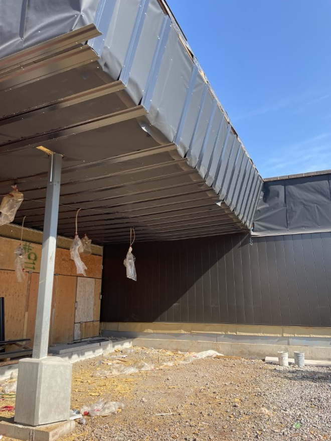 Exterior view of a building under construction with a metal roof