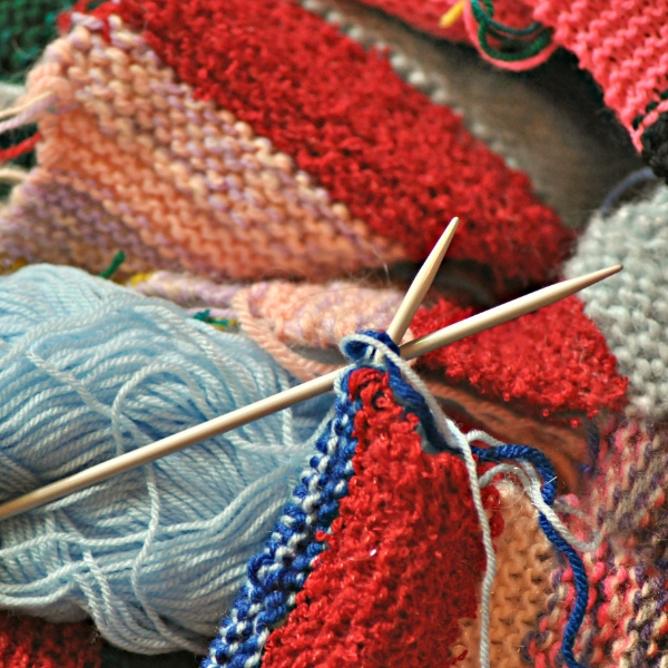 a pair of knitting needles, yarn, and knitted items