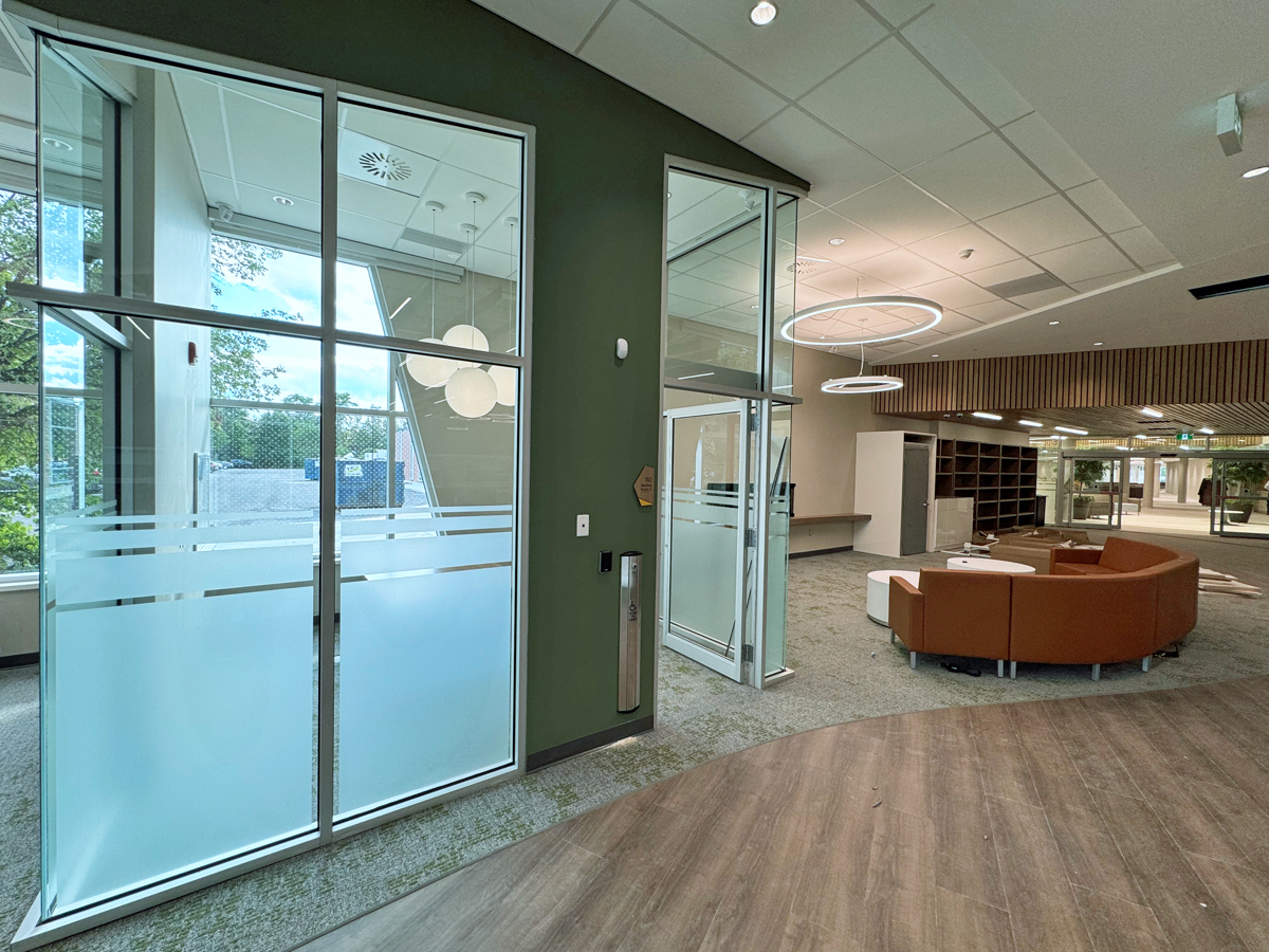 A glass-walled room beside a space with a couch