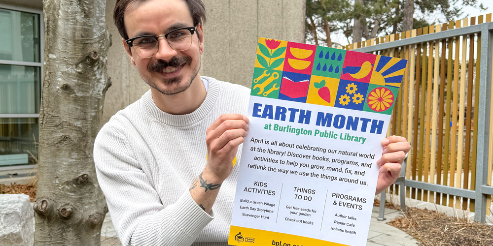 staff member holding up the BPL Earth Month poster