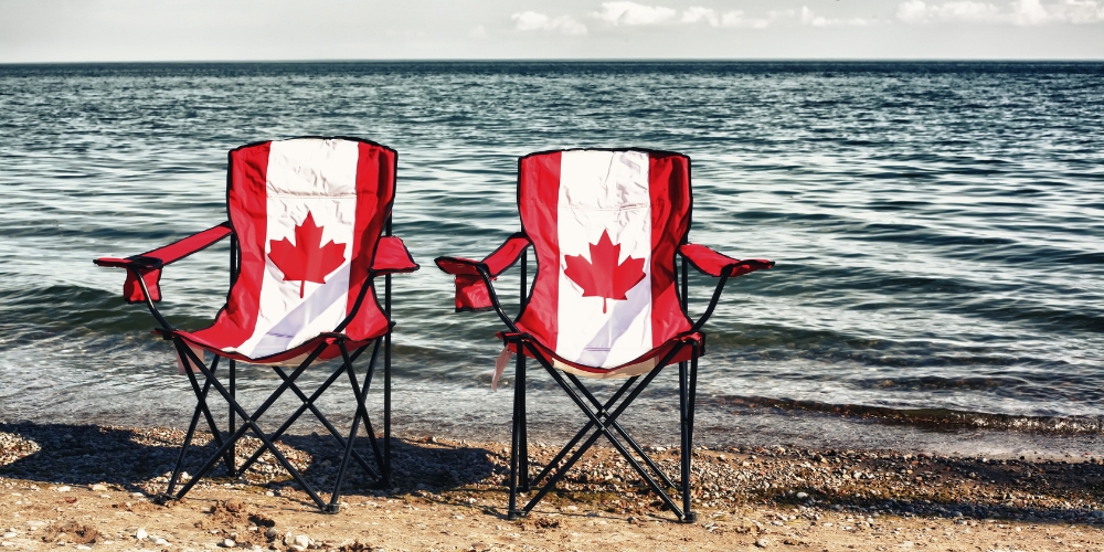 two folding beach chairs with a Canadian flag design by a lake