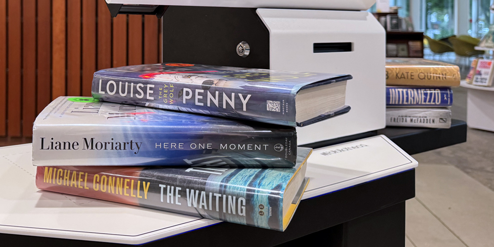 six books stacked on a self-checkout unit