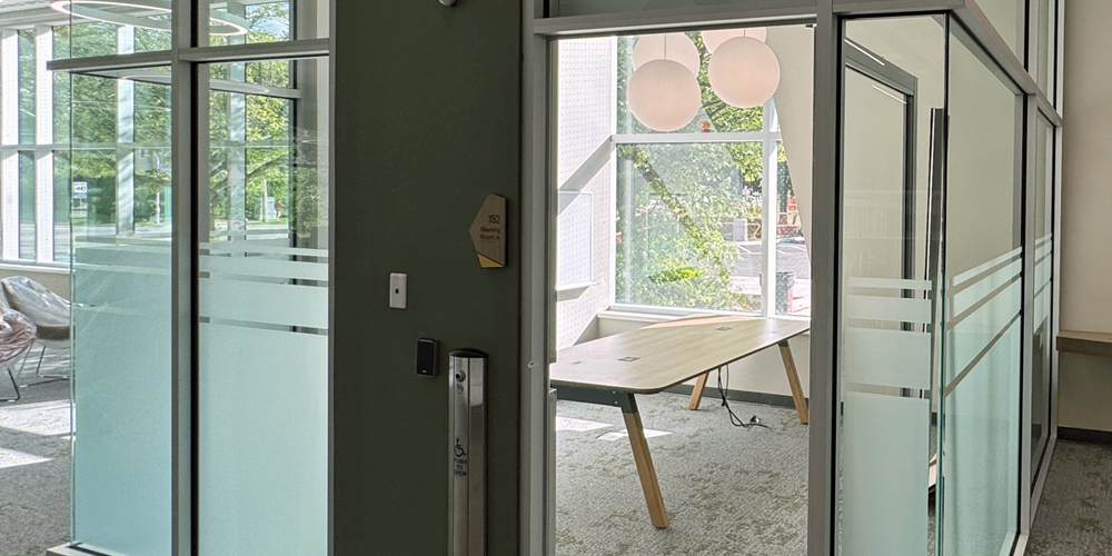 glass-walled meeting room with a wood table