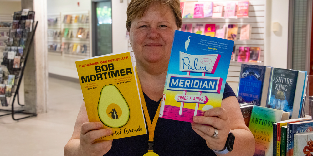 library staff member holding up two new books