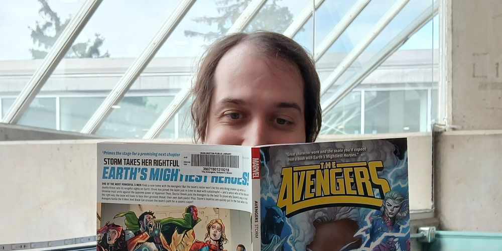 adult holding up a graphic novel The Avengers