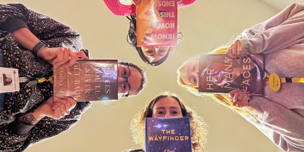 four staff each holding up a book