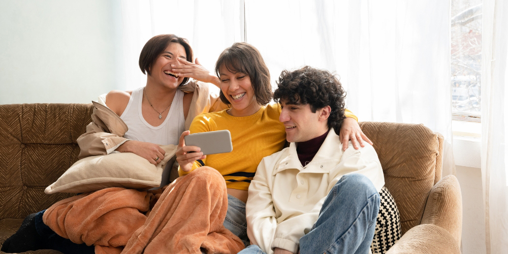 three adults sitting on a couch looking at a mobile phone