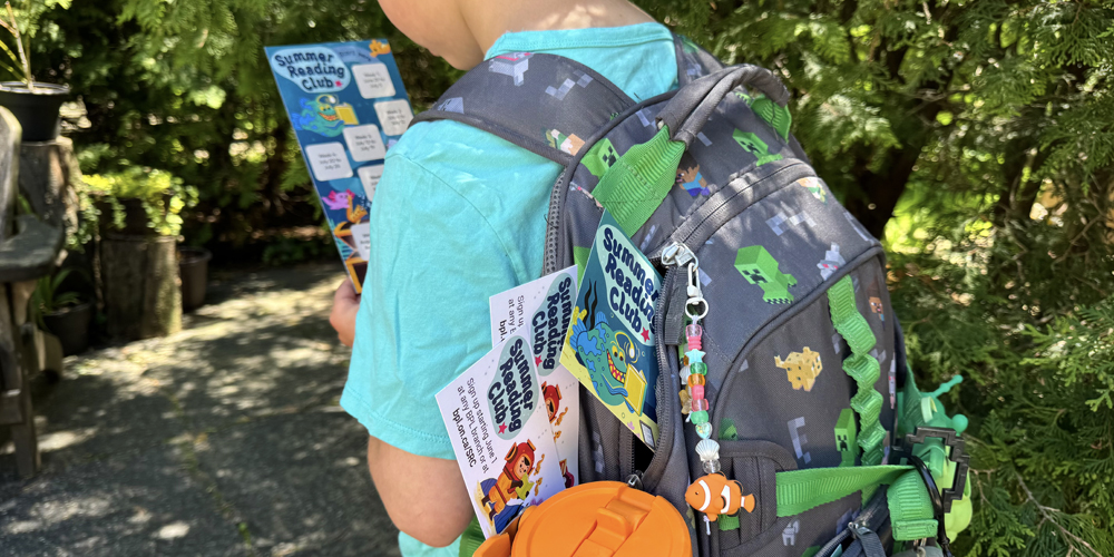 child wearing a backpack and looking at the reading club tracker