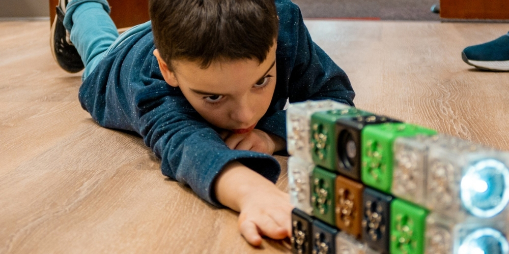 child lying on the floor and playing with Cubelets