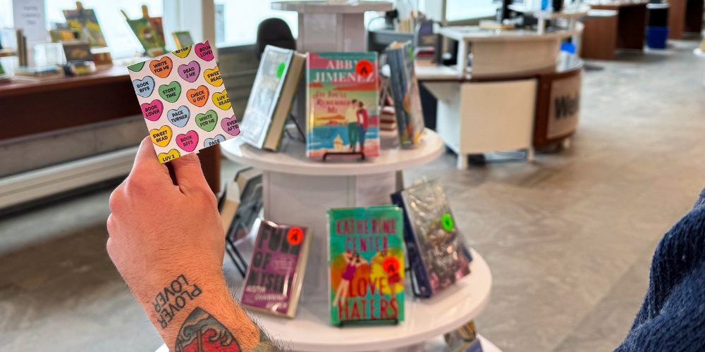 hand holding a Valentine with book displays in background
