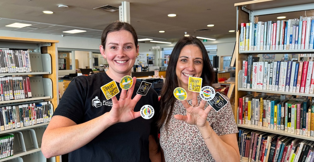 smiling library staff holding stickers