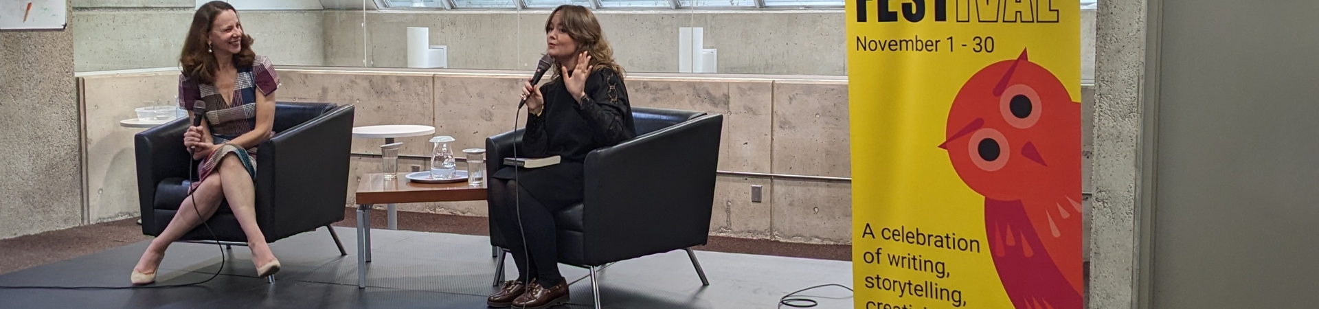 two adults seated on a stage holding microphones